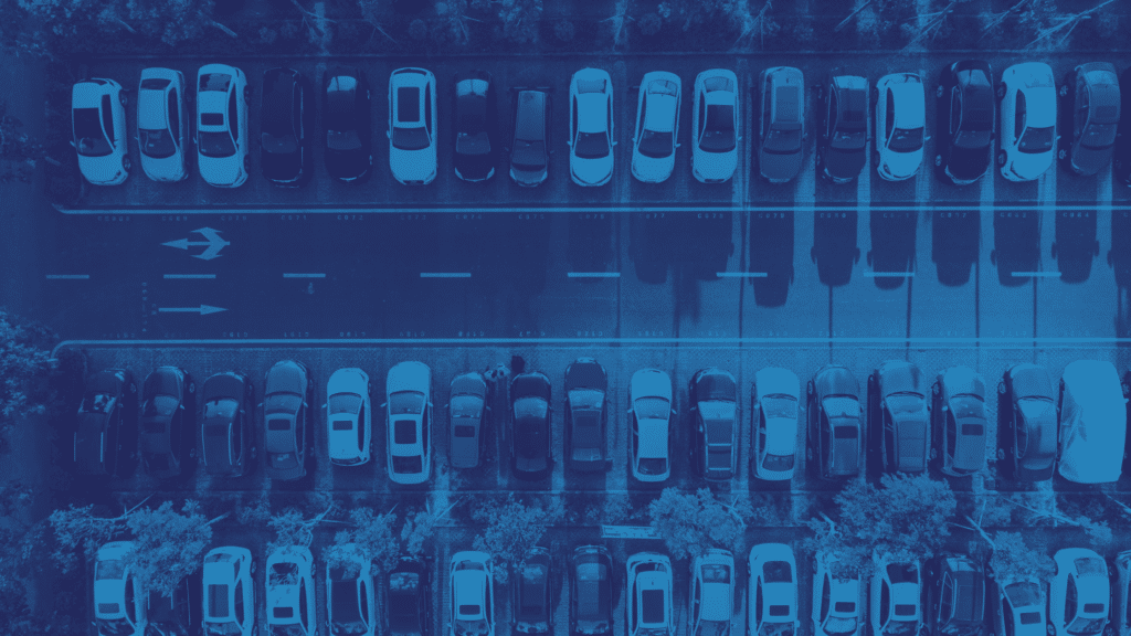 Aerial view of a parking lot featuring multiple rows of parked cars with a central road, showcasing efficient parking management.