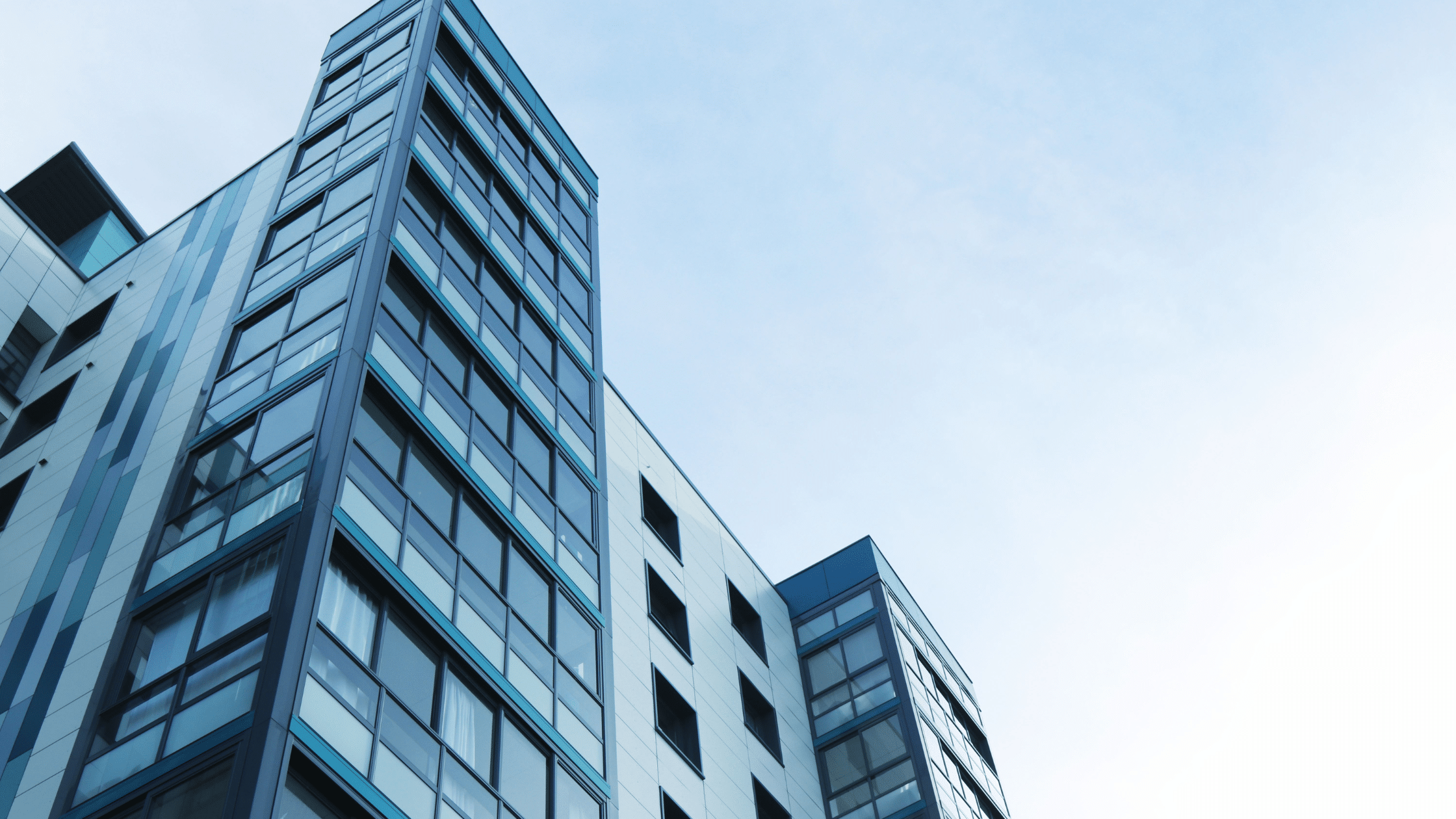 Modern high-rise building with blue and white exterior under a clear sky, featuring advanced parking management systems for seamless commercial parking.