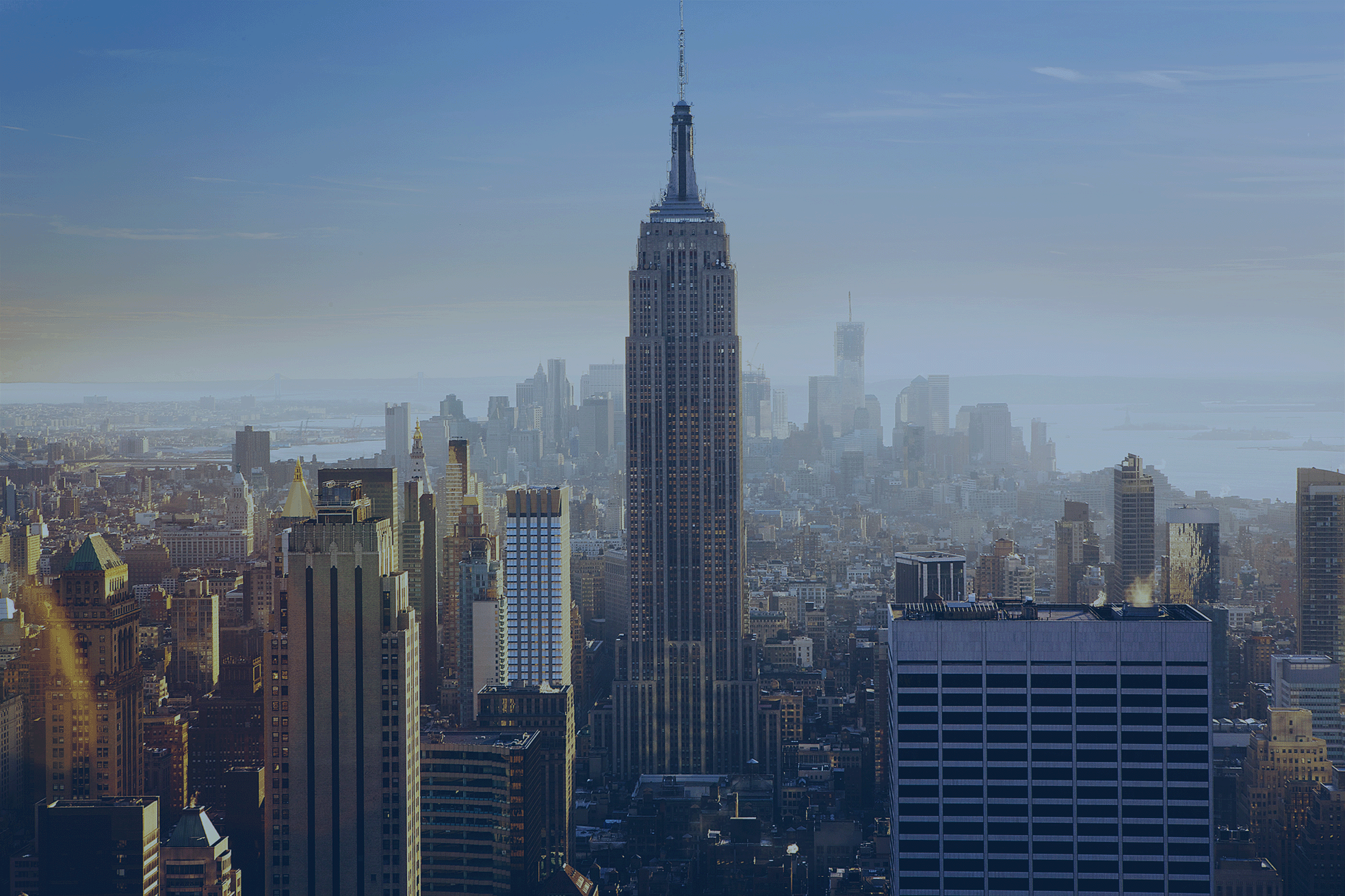 Aerial view of a city skyline featuring the Empire State Building surrounded by various skyscrapers against a clear blue sky. Cover to a guide demonstrating how to create parking space in NYC