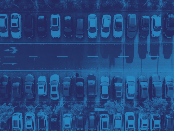 Aerial view of a parking lot featuring multiple rows of parked cars with a central road, showcasing efficient parking management.